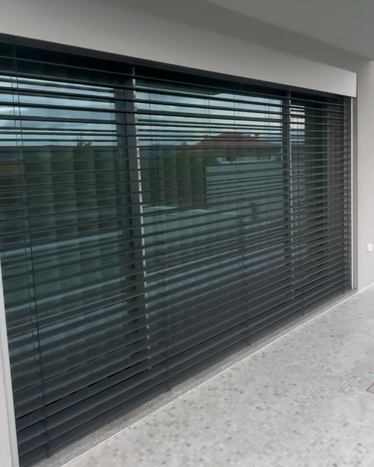 Brisas solares de lâminas orientáveis em antracite num envidraçado de varanda