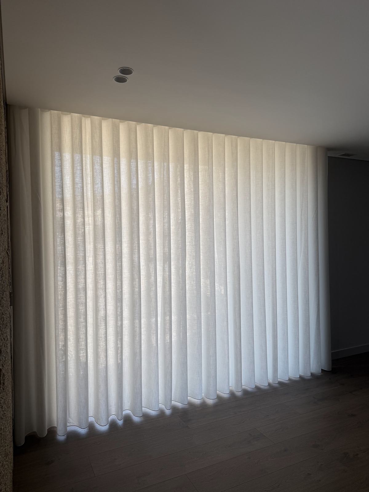 Cortinado de onda claro a cobrir uma parede inteira, do teto ao chão
