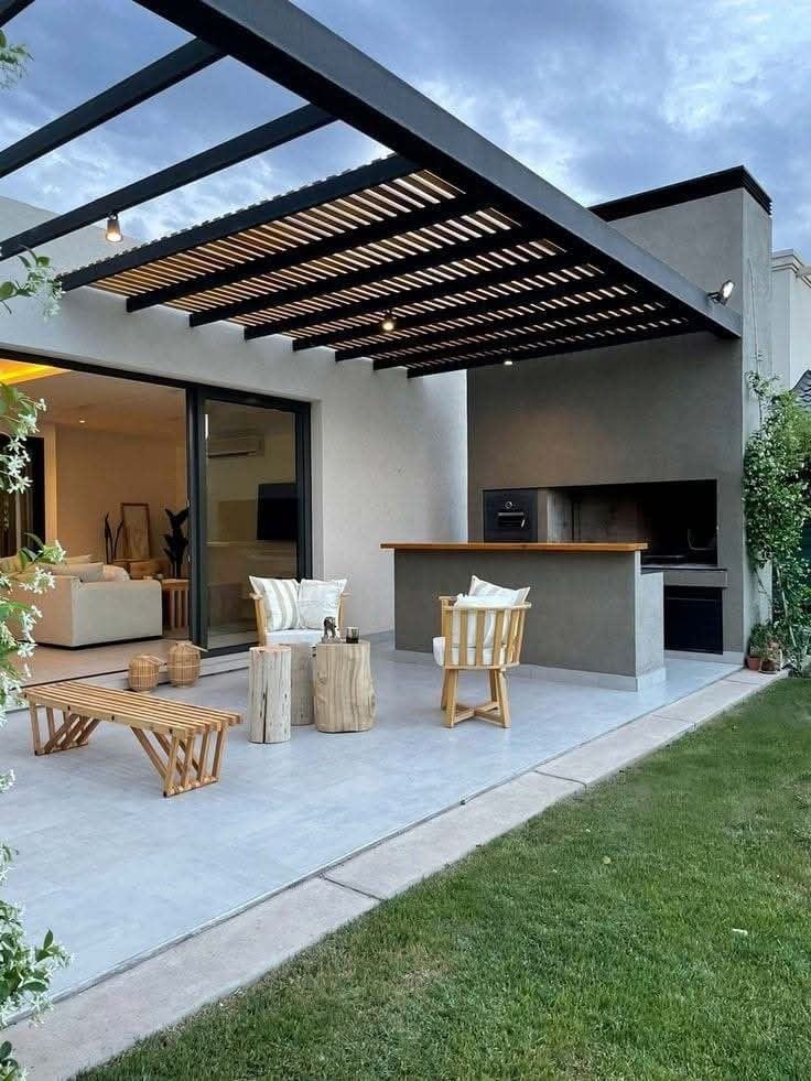 Pérgola de estrutura metálica com ripado de madeira sobre uma zona de churrasqueira